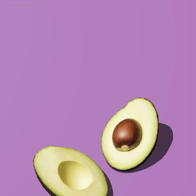 two halfs of an avocado against a purple background