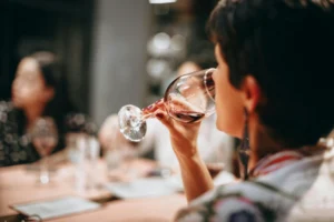 close up of woman taking a sip of wine in a group setting