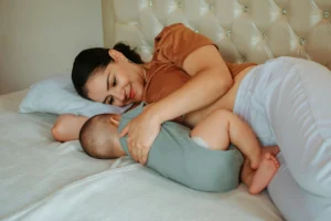 mother cradles her newborn baby in bed