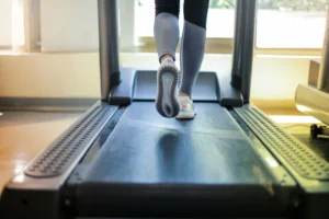 close up of a woman's feet as she runs on a treadmill