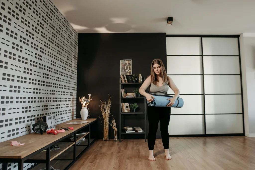 woman prepares to unroll yoga mat in an exercise studio