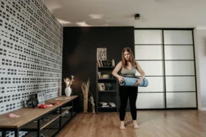 woman prepares to unroll yoga mat in an exercise studio