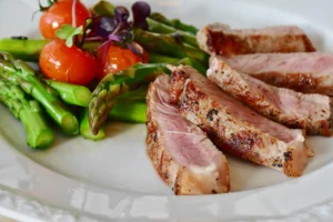 close up of meal containing steak, tomatoes and asparagus