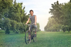 young male riding a bike in a grassy outdoor setting