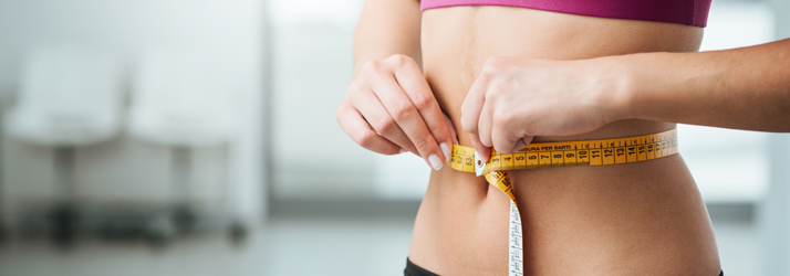 close up of woman measuring her waist