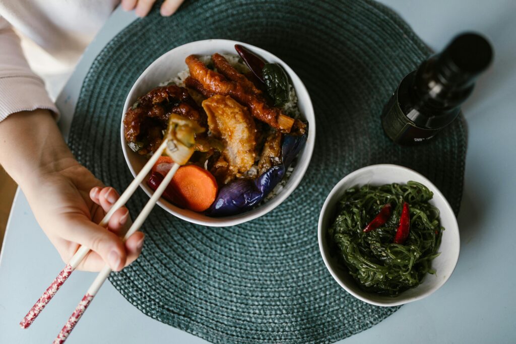close up of woman eating out of a bowl with chop sticks
